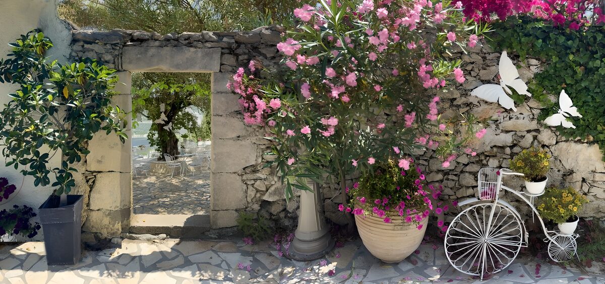 Alte Mauer mit Durchgang zum Innenhof und altes Fahrrad mit Blumen