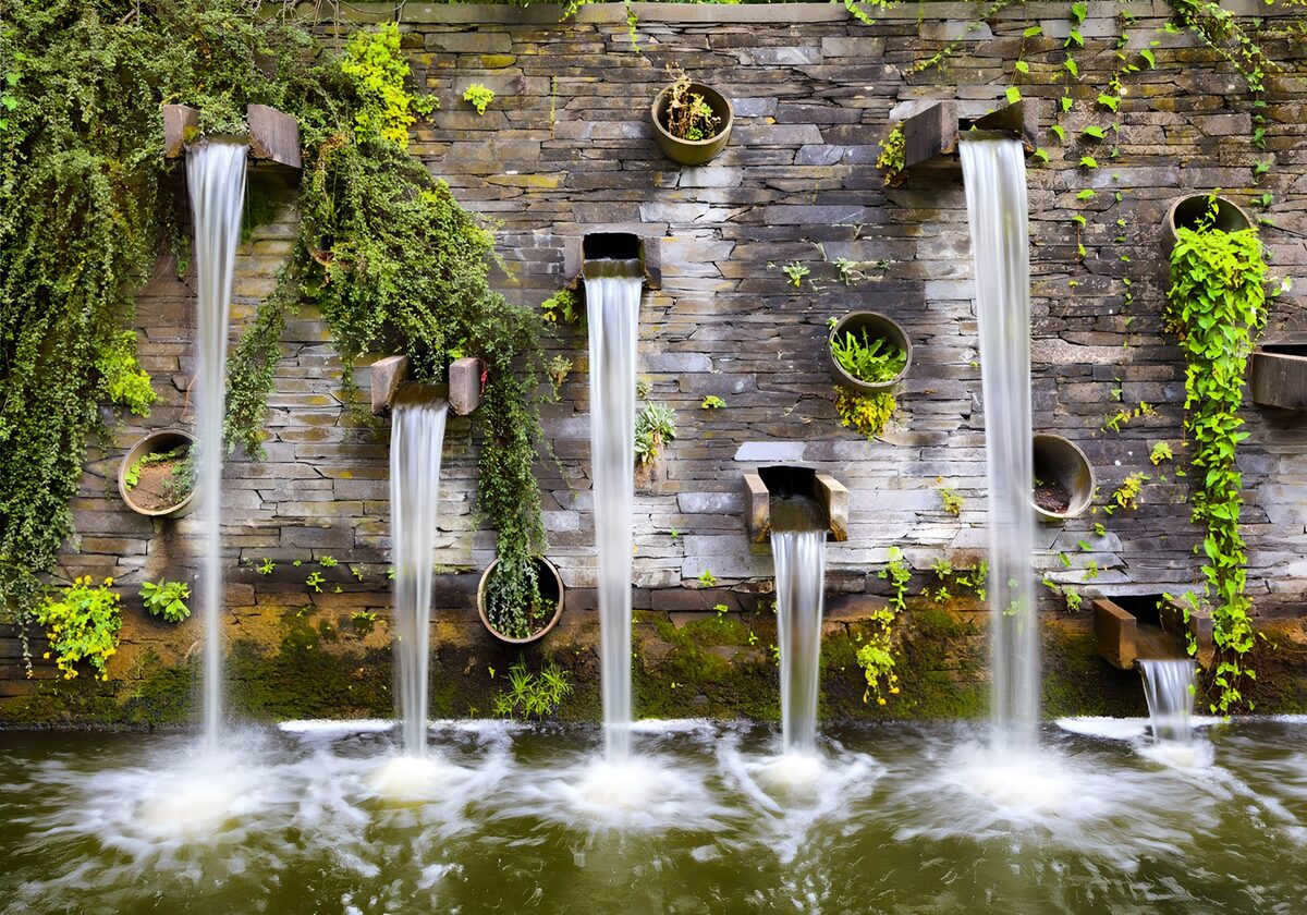 Mauer mit Wasserfall, überwuchert von Pflanzen