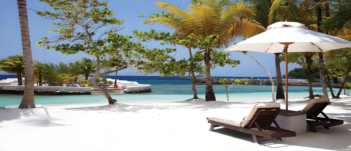 TPDE89304: Sonnenliegen im Schatten an einem weißen Strand
