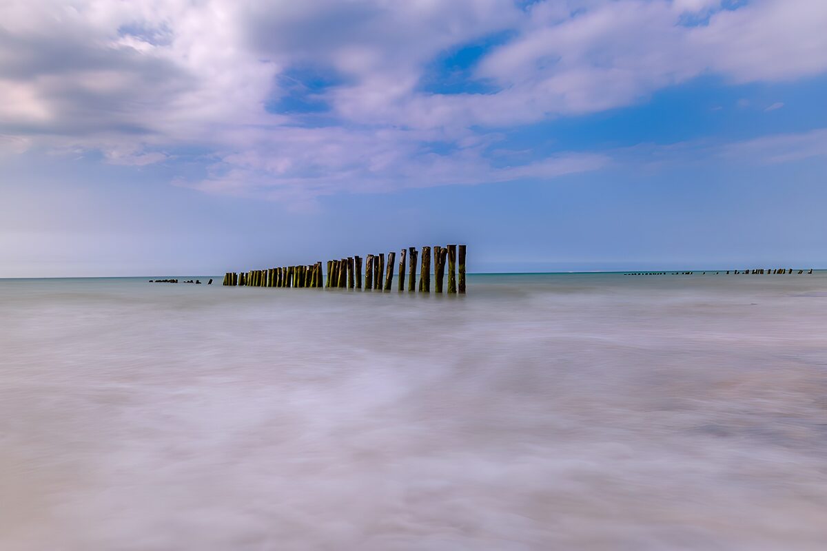 TPDE36907: Wellen und Pfähle am ruhigen Meer
