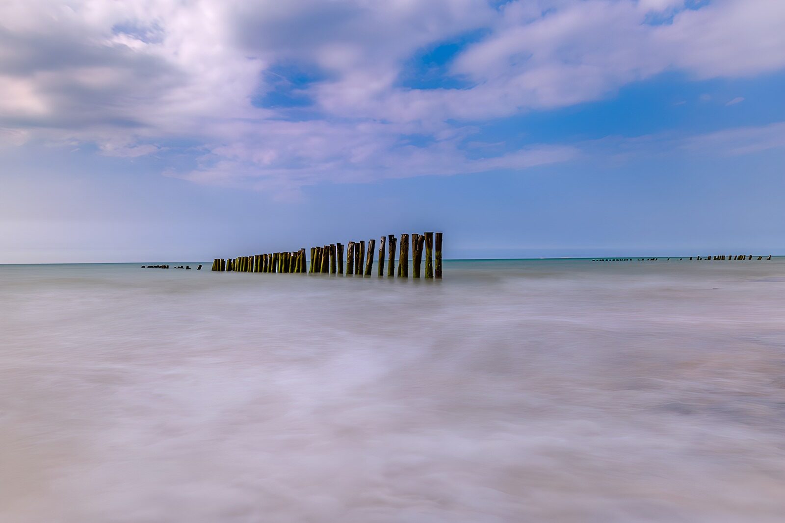 TPDE36907: Wellen und Pfähle am ruhigen Meer