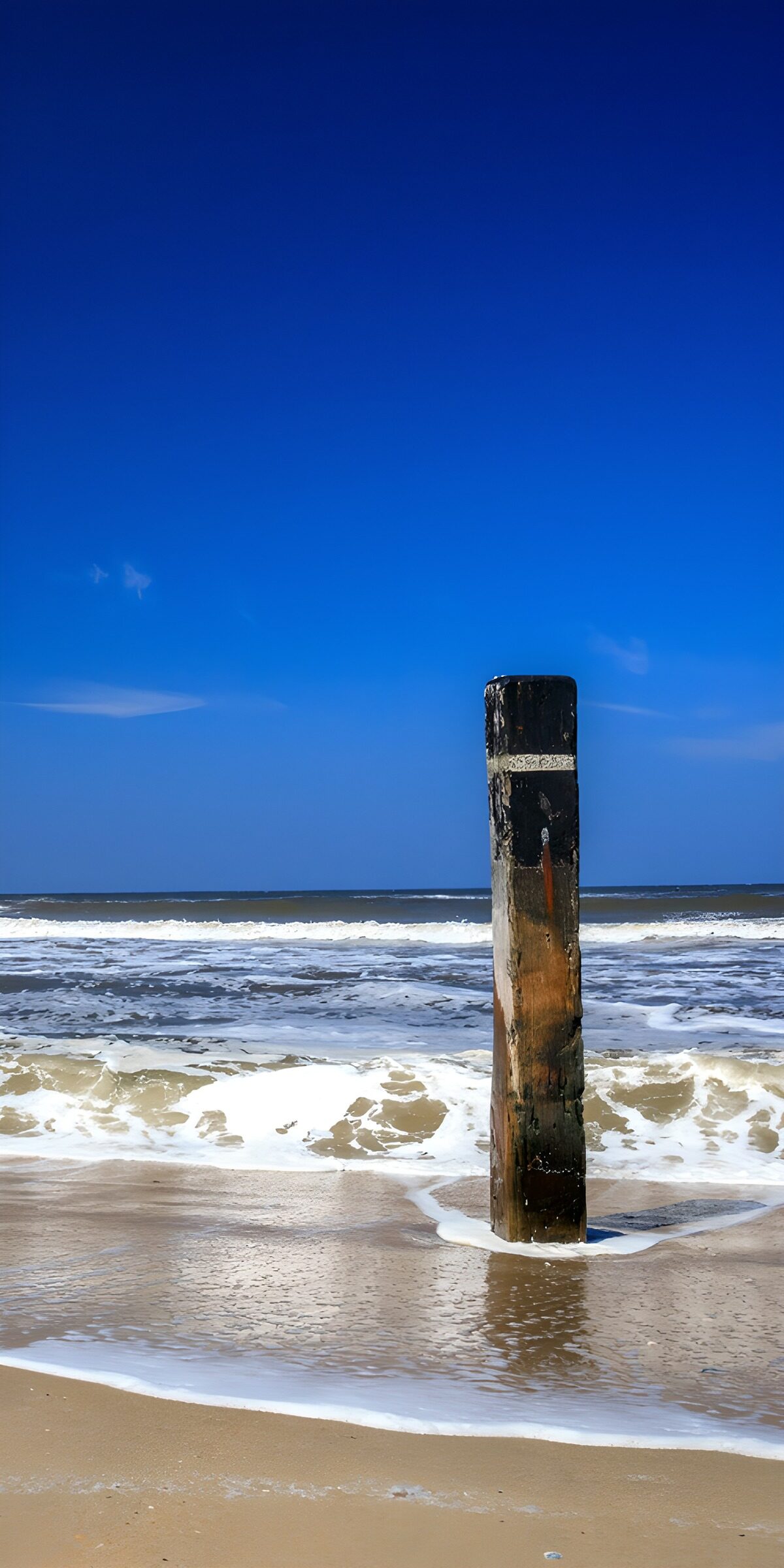 Holzpoller am Strand unter blauem Himmel
