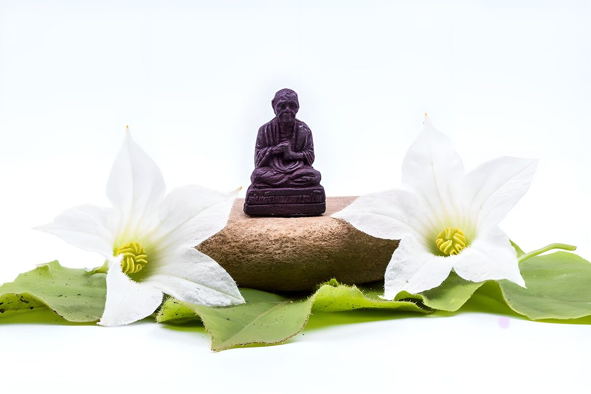 TPDE15609: eine Buddha auf einem Stein und rundherum Blüten und grünen Blättern