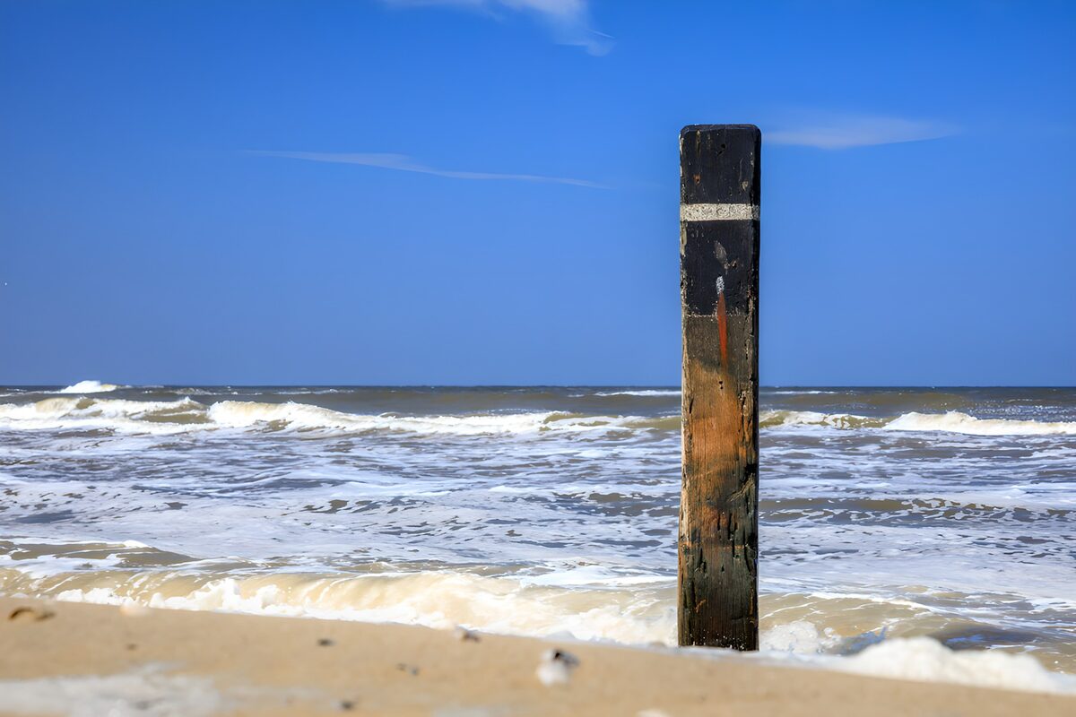 TPDE50594: Pfahl am Strand und Wellen
