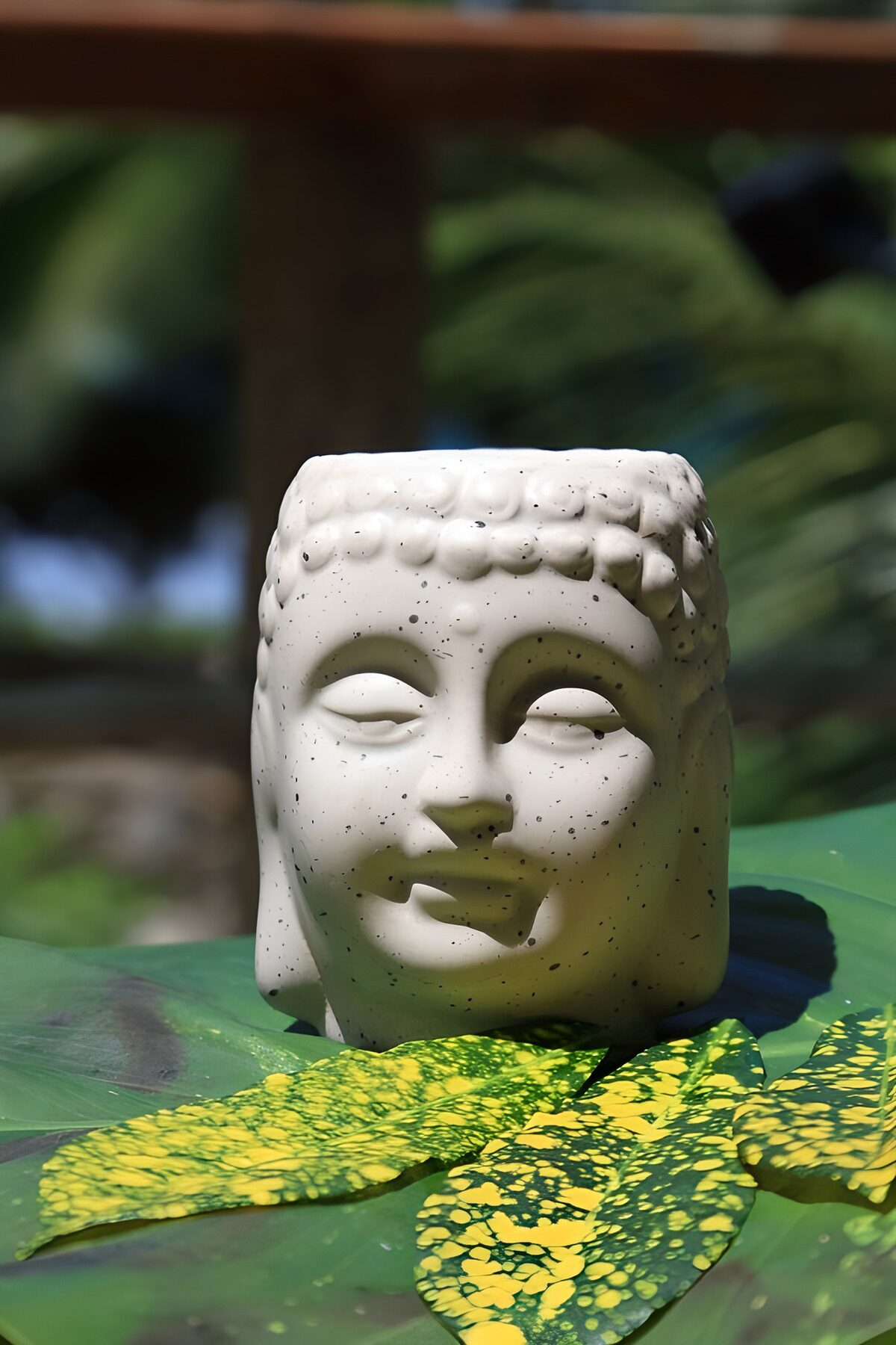 Buddha-Kopf auf grünen Blättern