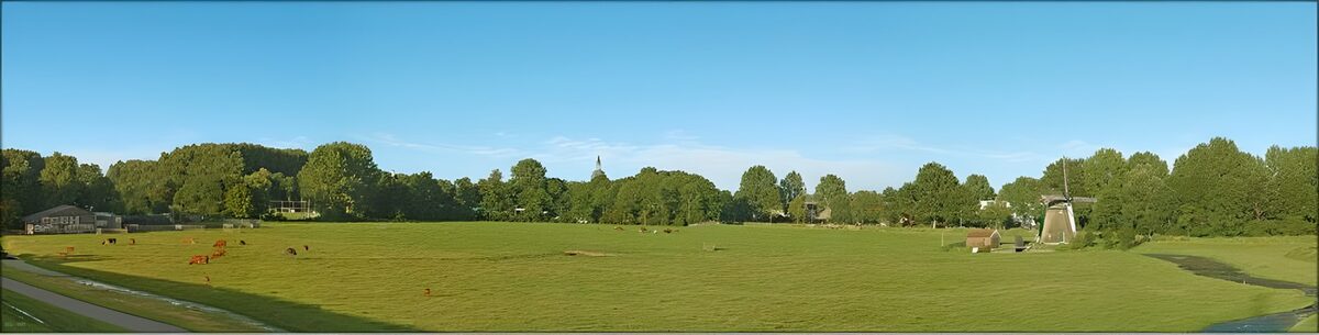 Radweg mit Blick auf eine Poldermühle, Kirchturm und Bauernhöfe