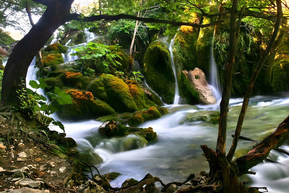 Wasserfall an Felsblöcken mit Moos vorbei