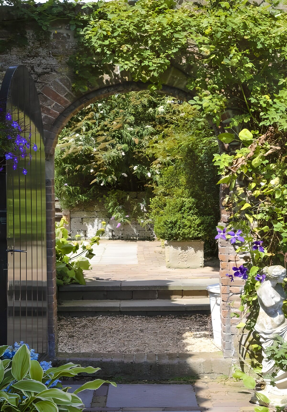 Tür zu einem  Hintergarten mit einem Mix aus bodendecker, Stauden und saisonalen Blumen