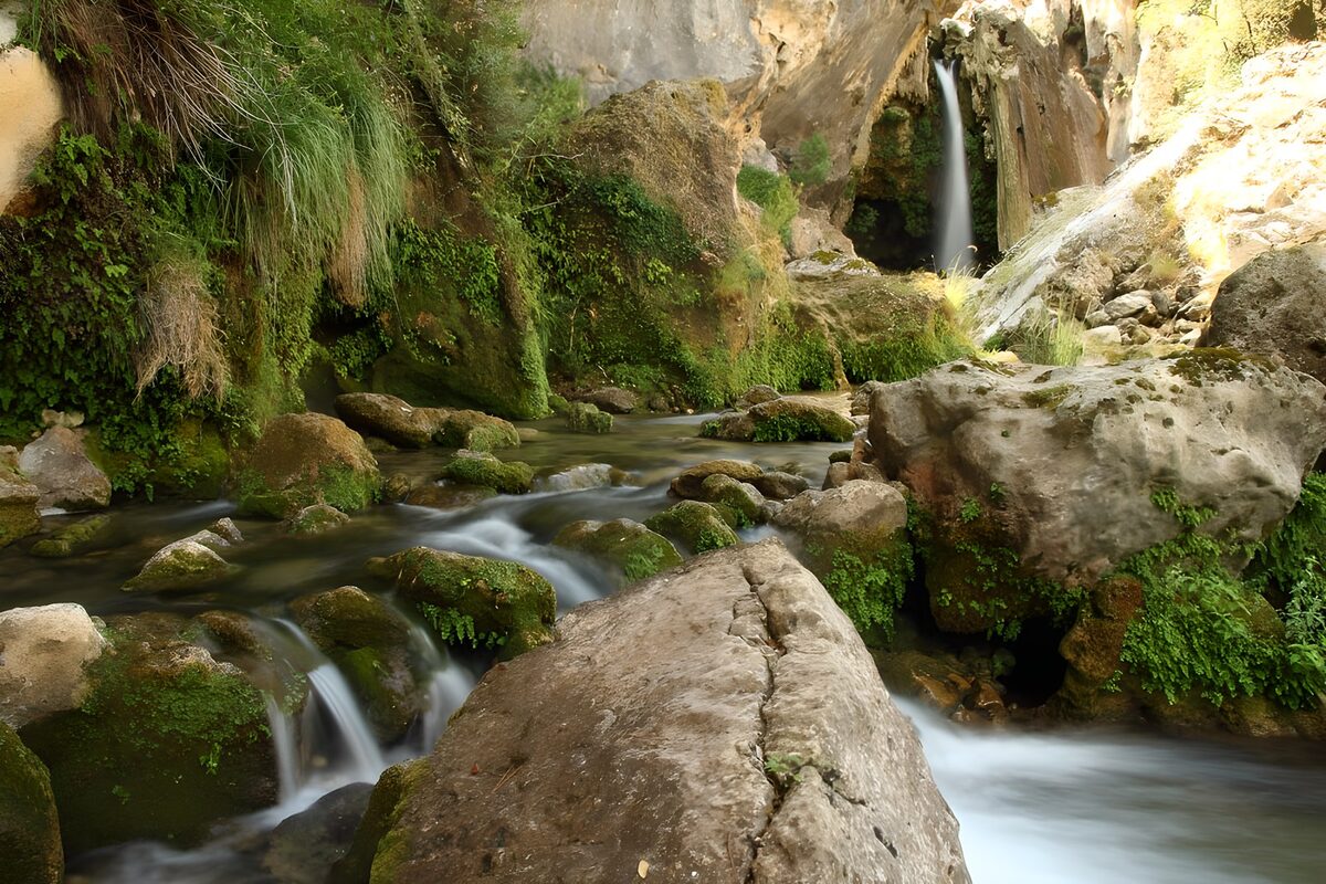 großer Wasserfall im Hintergrund, dessen Wasser über mehrere Felsen hinabfließt
