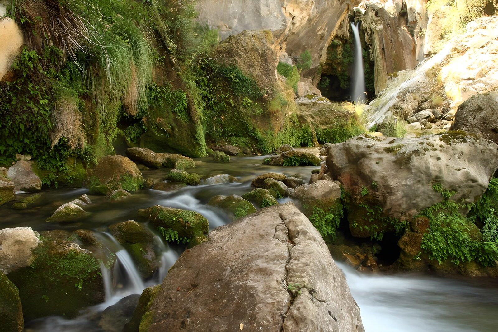 TPDE32412: großer Wasserfall im Hintergrund, dessen Wasser über mehrere Felsen hinabfließt