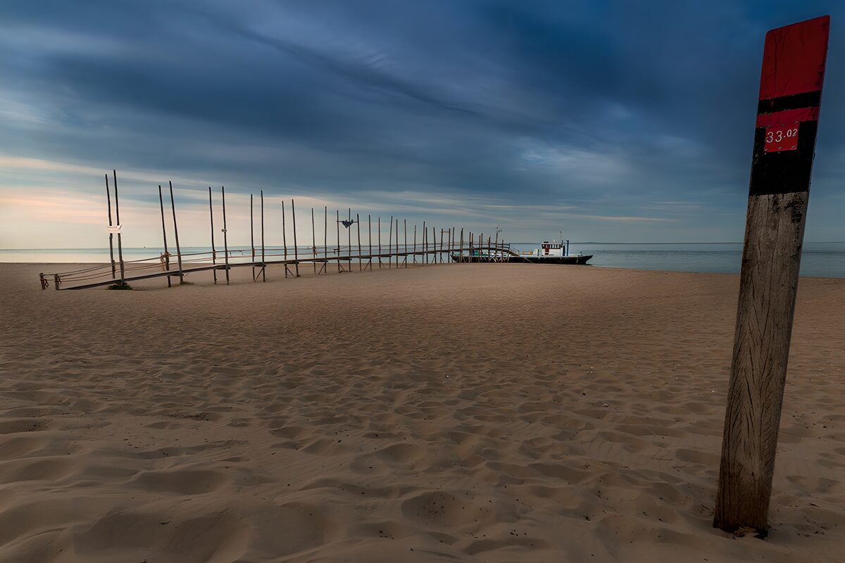TPDE97327: Ruhiger Strand mit Steg und Boot