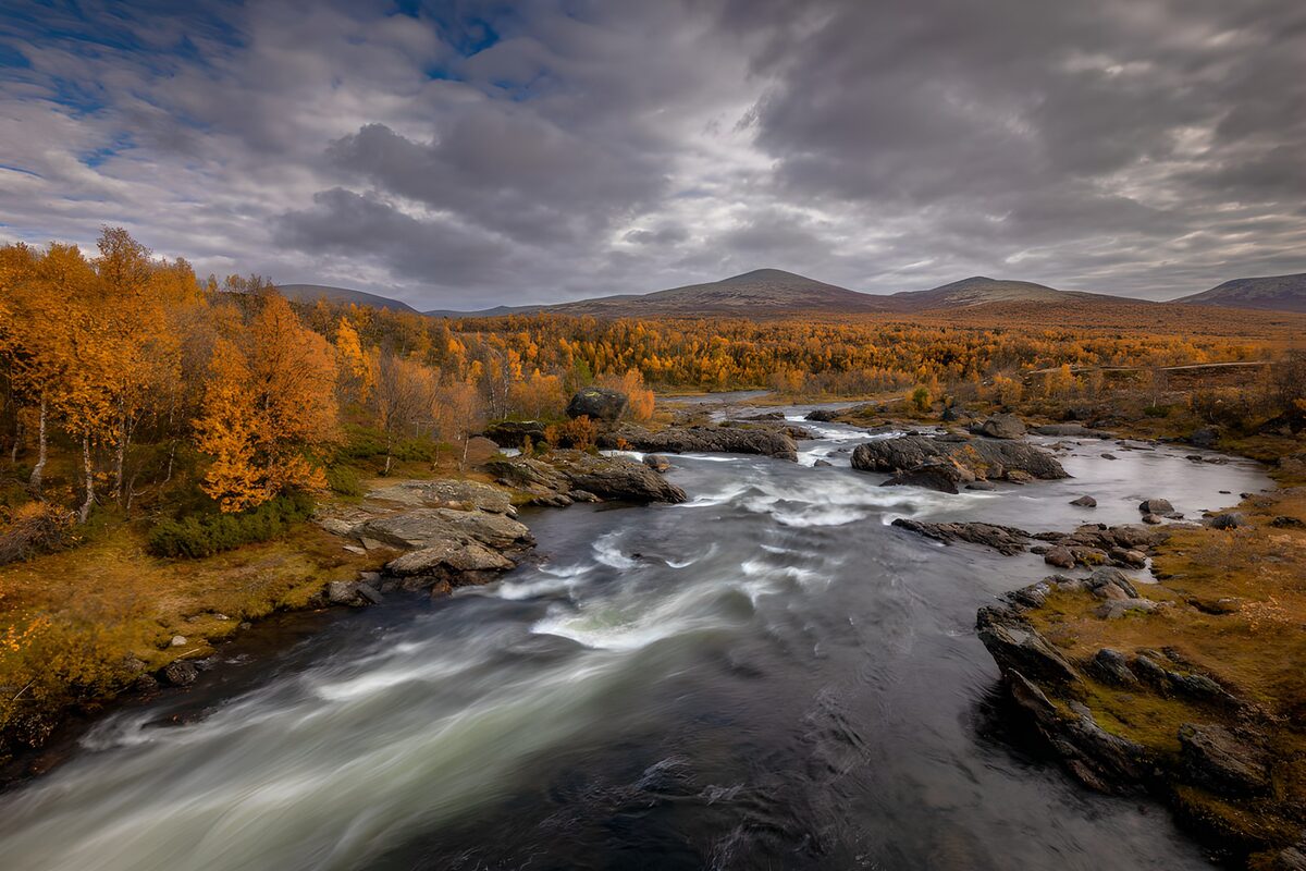 Herbstliche Landschaft mit Fluss und Bergen